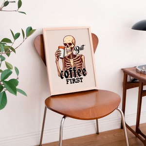 May include: A framed print with a skeleton holding a cup of coffee. The text on the print reads "But coffee first."
