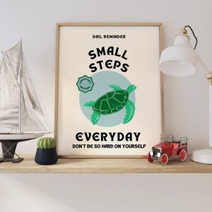 Pu&ograve; includere: Un poster motivazionale con una tartaruga marina verde su uno sfondo blu. Il poster dice "Promemoria quotidiano: Piccoli passi ogni giorno. Non essere troppo duro con te stesso." e ha un cerchio verde con le parole "La costanza conta" al suo interno.