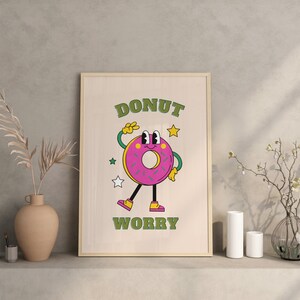 May include: A framed print with a cartoon donut character with the text "DONUT WORRY" in green letters on a light wood background.