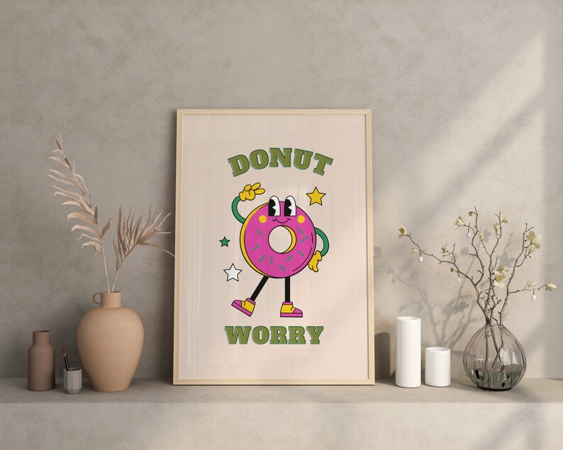 May include: A framed print with a cartoon donut character with the text "DONUT WORRY" in green letters on a light wood background.