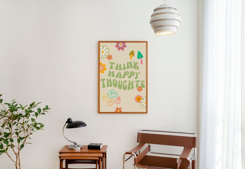 May include: A framed print with a light beige background and green text that reads "Think Happy Thoughts". The text is surrounded by colorful flowers and smiley faces.
