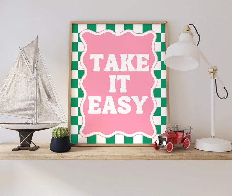 May include: A framed print with a green and white checkered background and a pink speech bubble with the text "TAKE IT EASY" in white letters.