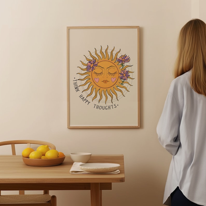 Puede incluir: Una impresi&oacute;n enmarcada con un sol amarillo con una cara de ojos cerrados y dos corazones rosas en las mejillas. El sol est&aacute; rodeado de flores moradas y el texto "Think Happy Thoughts." est&aacute; escrito alrededor del sol.