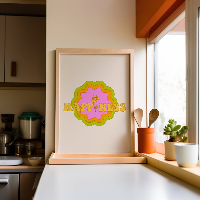 May include: A framed vertical print featuring the word HAPPINESS in yellow block letters. The text is centered over a pink, orange, and lime green scalloped circular graphic with a small yellow flower illustration replacing the letter I.