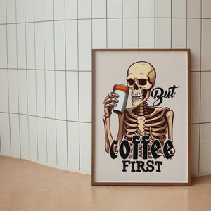 May include: A framed illustration of a skeleton holding a coffee cup with the text "But coffee first".