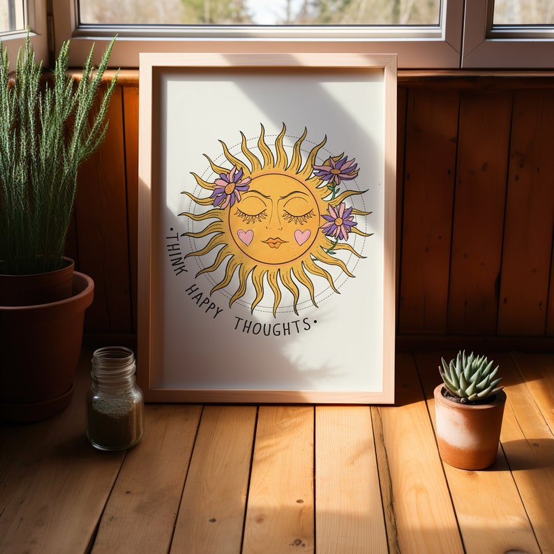 Puede incluir: Una impresi&oacute;n enmarcada con un sol amarillo con cara y ojos cerrados. El sol est&aacute; rodeado de flores moradas y el texto "Think Happy Thoughts."