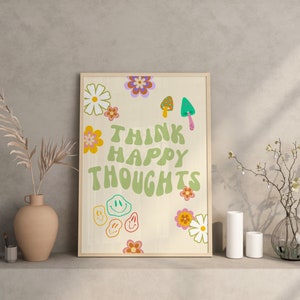 May include: A framed print with a white background and green text that reads "Think Happy Thoughts". The print is decorated with colorful flowers, mushrooms, and smiley faces.