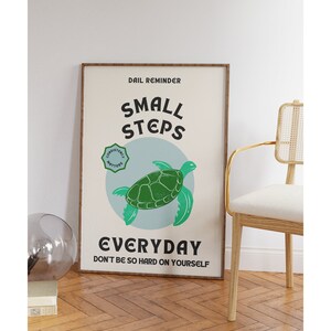 Pu&ograve; includere: Un poster motivazionale con una tartaruga marina verde su uno sfondo blu. Il poster recita "Promemoria quotidiano: Piccoli passi ogni giorno. Non essere troppo duro con te stesso." e ha un cerchio verde con il testo "La costanza conta" nell'angolo in alto a sinistra.