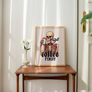 May include: A framed print with a skeleton holding a cup of coffee. The text on the print reads "But coffee first."