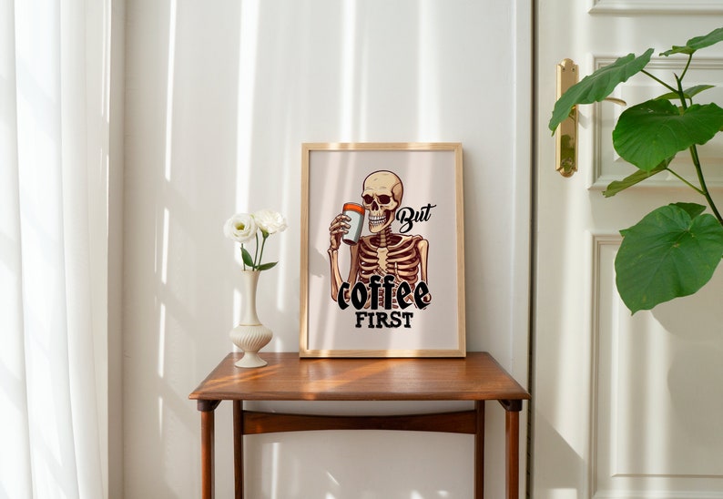 May include: A framed print with a skeleton holding a cup of coffee. The text on the print reads "But coffee first."