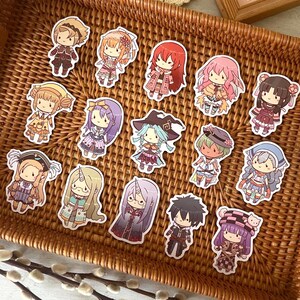 以下が含まれることがあります： アニメスタイルのカラフルなキャラクターのステッカーのコレクションが、編まれた柳のトレイに配置されています。ステッカーは、ユニークな衣装と髪型を持つさまざまなキャラクターを特徴としています。トレイは茶色で、白い表面に置かれています。