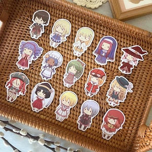 May include: A selection of anime-style character stickers on a woven wicker tray. The stickers depict various characters in different outfits and hairstyles, with a cute, cartoonish aesthetic. The tray is brown and the stickers are colourful.