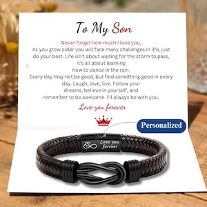 Op de afbeelding: Een zwart leren armband met een zilveren oneindigheidssymbool en de woorden "Love you forever" gegraveerd op een metalen plaat. De armband is met een knoop vastgemaakt en heeft een gepersonaliseerd bericht.