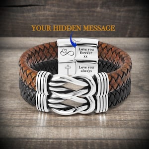 Könnte beinhalten: Ein braunes und schwarzes Lederarmband mit einem silbernen Verschluss und einer versteckten Botschaft, die in den Verschluss graviert ist. Die Botschaft lautet "Love you forever xx" und "Love you always".