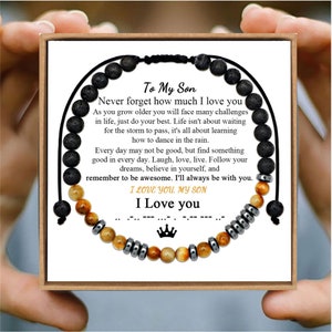 May include: A black lava rock and tiger's eye beaded bracelet with a message card that reads "To My Son, Never forget how much I love you. As you grow older you will face many challenges in life, just do your best. Life isn't about waiting for the storm to pass, it's all about learning how to dance in the rain. Every day may not be good, but find something good in every day. Laugh, love, live. Follow your dreams, believe in yourself, and remember to be awesome. I'll always be with you. I LOVE YOU. MY SON I Love you".