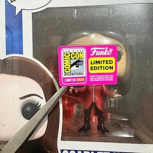 Puede incluir: Una figura Funko Pop de vinilo con cabeza oscilante de Scarlet Witch de Captain America Civil War en su embalaje original. La caja incluye una pegatina rosa de San Diego Comic-Con International Limited 2026 y muestra el nombre del personaje.
