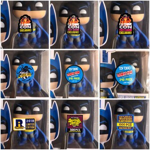 May include: Nine Batman Funko Pop figures in packaging, each with a Comic Con exclusive sticker. Stickers display text including "L.A. Comic Con Exclusive!", "Toy Tokyo Comic Con", and "Saturday Morning Cartoons". A collectible item.