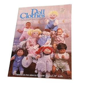 May include: A vintage book cover titled "Doll Clothes" featuring illustrations of various dolls in different outfits. The cover includes text for doll sizes and brands like Cabbage Patch and Thumbelina. The dolls are dressed in pastel colors.