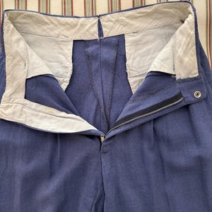 K&ouml;nnte beinhalten: Nahaufnahme einer blauen Hose mit Rei&szlig;verschluss und Knopfverschluss. Die Hose hat ein wei&szlig;es Futter am Bund und Falten vorne. Der Stoff scheint ein mittelschweres Material zu sein.