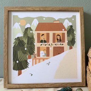 May include: A framed illustration of a family of three standing in the windows of a house in a snowy landscape. The house is brown with white trim and a red roof. The family is wearing winter clothes and smiling. The illustration is set against a background of green trees and white snow.