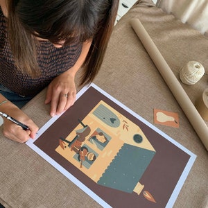 May include: A brown and yellow illustration of a house with a blue roof and a lit candle. The house has a window with a heart shape and a family of four inside. The illustration is on a brown background.