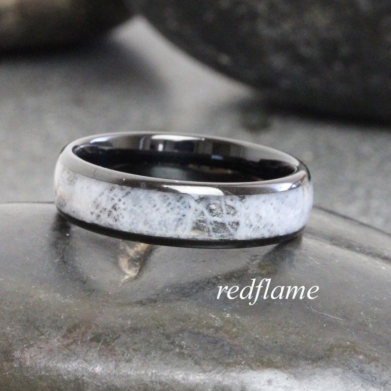 May include: A black ring with a white, textured inlay. The ring has a polished finish and is set against a dark background. The text "redflame" is in the lower right corner.