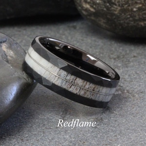 May include: A black and white ring with a textured surface. The ring features a central band of light-colored material, framed by black bands and thin silver lines. The word "Redflame" is at the bottom of the image.