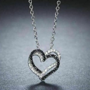May include: A silver necklace with a black and white diamond heart pendant.