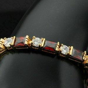May include: A gold bracelet with red and clear square-shaped stones.