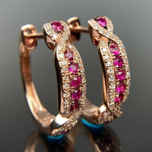 Peut inclure: Une paire de boucles d'oreilles créoles en or rose avec un design torsadé. Les boucles d'oreilles sont serties de petits rubis ronds et de diamants.