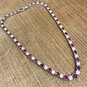 Könnte beinhalten: Eine silberne Halskette mit einer Reihe von rosafarbenen Edelsteinen und kleineren weißen Edelsteinen.