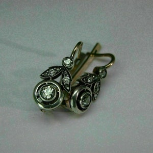 May include: A pair of silver and gold earrings with a floral design and clear gemstones.