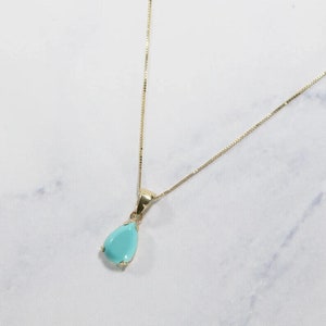 Può includere: Una collana con catena d'oro con un ciondolo a forma di lacrima con una pietra preziosa blu chiaro.