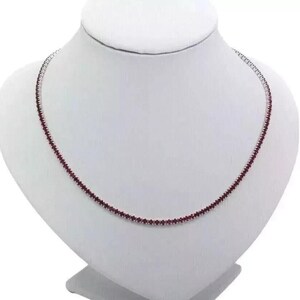 May include: A silver chain necklace with small, dark red gemstones.