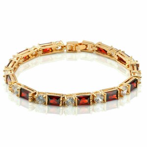 Pode incluir: Uma pulseira de ouro com pedras retangulares vermelhas e brancas. A pulseira tem um fecho de encaixe.