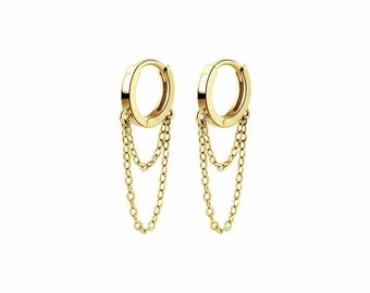 May include: Gold hoop earrings with two dangling chains. The hoops are simple and the chains are delicate.
