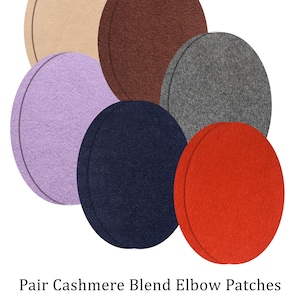 Könnte beinhalten: Eine Sammlung runder Ellbogen-Patches in Beige, Braun, Grau, Lavendel, Marineblau und Rot. Der Text "Pair Cashmere Blend Elbow Patches" und "More colors & sizes available" erscheint unter den Patches, begleitet von einem kleinen Garnrollensymbol.