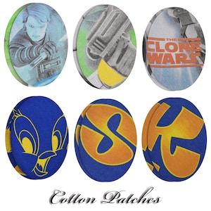 Puede incluir: Una colección de seis parches ovalados de algodón. Los parches presentan varios diseños, incluyendo personajes y logotipos de "Star Wars: The Clone Wars" y un personaje de dibujos animados. Los parches son azules, amarillos, verdes y blancos. El texto "Cotton Patches" está en la parte inferior.