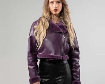 May include: A purple leather jacket with a faux fur collar and zipper closure. The jacket is cropped and has a fitted silhouette.