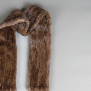 Puede incluir: Una bufanda de piel marr&oacute;n con un dise&ntilde;o largo y fluido. La bufanda est&aacute; hecha de piel suave y lujosa y es perfecta para a&ntilde;adir un toque de elegancia a cualquier atuendo.