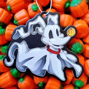 May include: A Halloween-themed air freshener featuring a cartoon ghost dog with a red collar and a pumpkin. The air freshener is black and white with a white string for hanging. The background is a pile of orange and green candies.