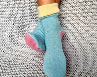 May include: A pair of socks with a light blue base color, a pink heel and toe, and a yellow cuff.