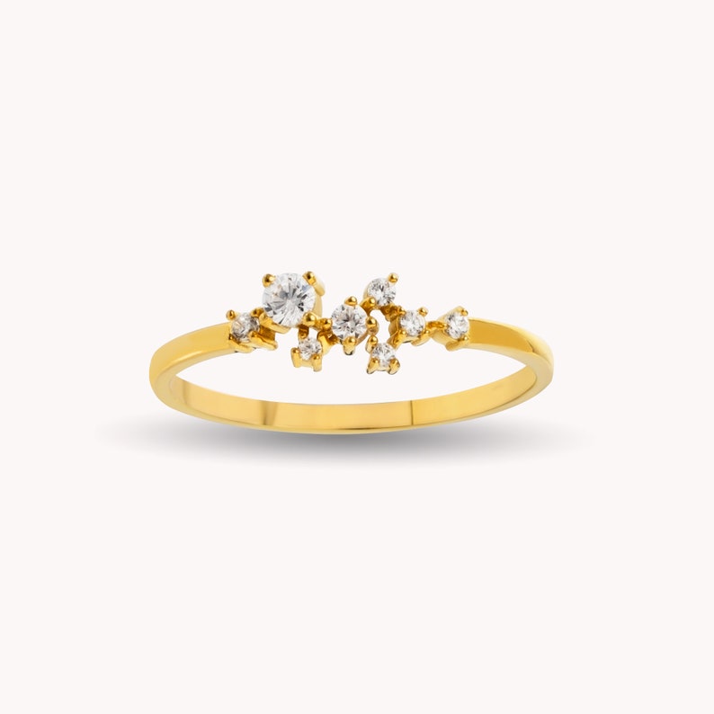 Pu&ograve; includere: Un anello con fascia in oro con un gruppo di piccoli diamanti trasparenti incastonati in un motivo disperso.