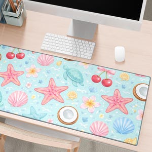May include: A rectangular desk mat with a light blue background featuring a pattern of pink starfish, seashells, turtles, cherries, and flowers. The mat has a gray border and the text "echo desk studio" in a green square.