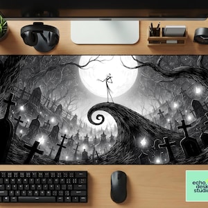 May include: A black and white desk mat featuring a spooky graveyard scene with a full moon and a character standing on a hill. The mat has a keyboard, mouse, and the "echo desk studio" logo.