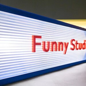 May include: A blue and white sign with the text "Funny Studio" in red letters.