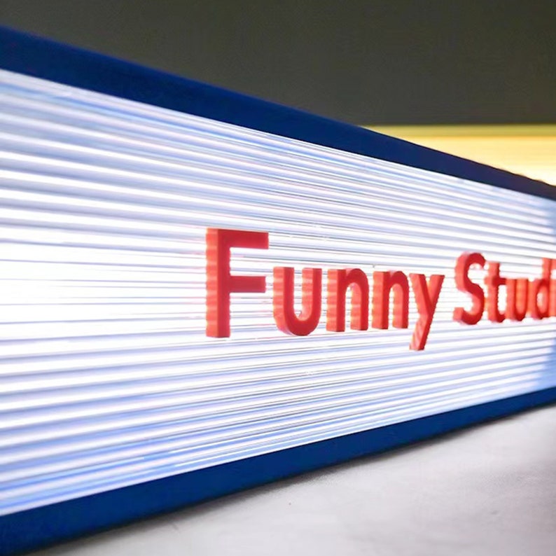 May include: A blue and white sign with the text "Funny Studio" in red letters.