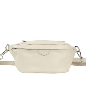 May include: A cream-colored leather fanny pack with a silver buckle and adjustable strap.