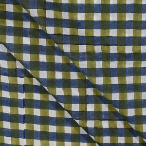 Op de afbeelding: Een textielstof met een herhalend vichy-ruitpatroon in olijfgroen, marineblauw en wit. Het materiaal is diagonaal over het midden gevouwen, waardoor het consistente rasterontwerp over het gehele oppervlak van de stof zichtbaar is.