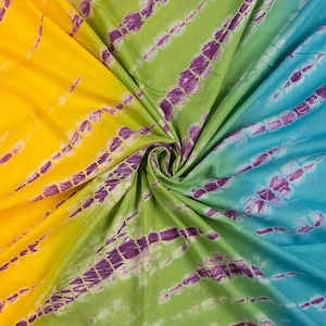 Puede incluir: Una tela vibrante con un diseño tie-dye. La tela está dividida en secciones amarillas, verdes y azules. Cada sección presenta rayas moradas. La tela está arrugada en el centro, creando un efecto de remolino.